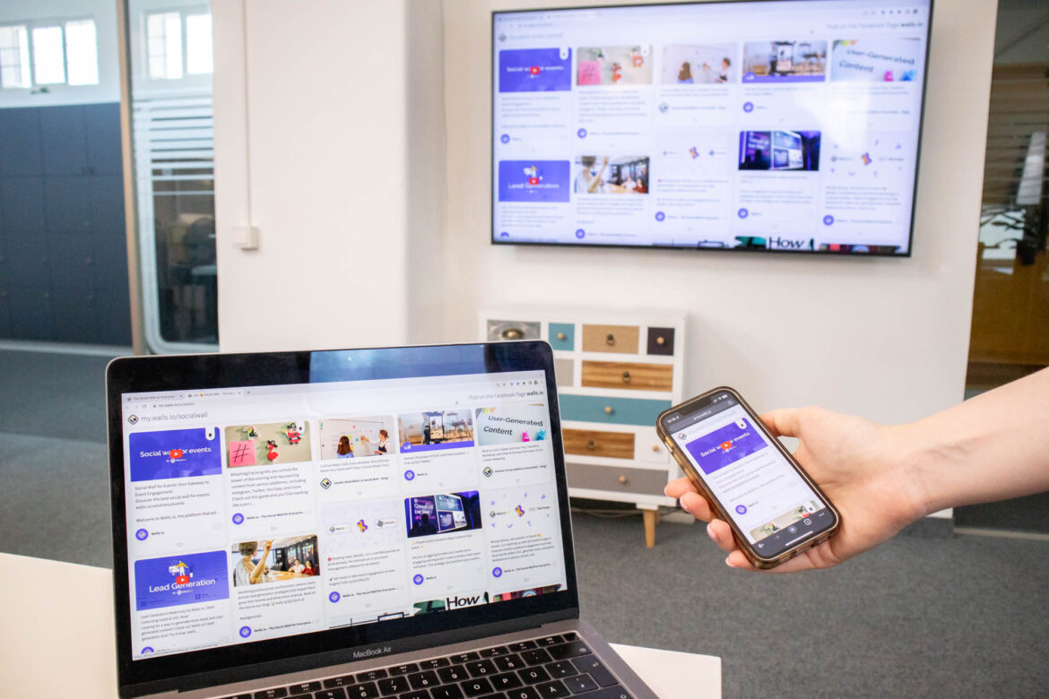 A laptop, smartphone, and large screen display the same Walls.io social wall filled with user-generated posts. The setup shows how Walls.io works seamlessly across multiple devices.